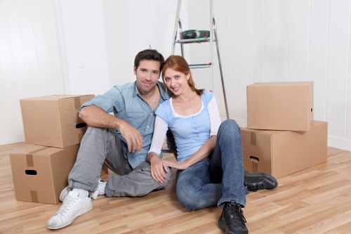 Moving team handling boxes and furniture in a West London home